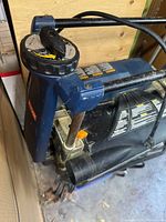 Close-up of Ryobi planer's depth adjustment knob, part of the metal framework, and instruction labels.