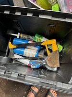 Tool box contents showing yellow caulking gun, putty knife, blue torch canisters, and utility knife