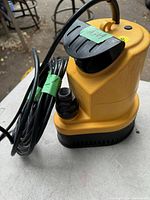 Yellow Moindini branded utility and sump pump with power cord coiled beside it.