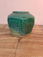 Front angle view of hexagonal green glazed antique Chinese ginger jar showing floral embossed pattern
