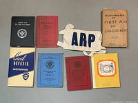 Overview of all items in the lot, showing the ARP armband and eight related civil defence and first aid books.