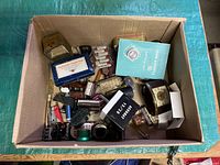 Top-down view of assorted vintage trinkets including Caribonum stamp pad, exposure meter manual, various lighters, and a small vintage clock
