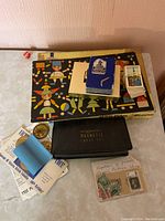 Photo shows full lot on white surface including black magnetic chess set box labeled Majestic, cards and envelopes with replica stamps, blue dice, and colorful illustrated building blocks box.