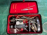 Top view of the microscope and accessories inside the open carrying case with red interior.