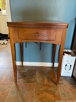 Front view of the wooden sewing table showing single drawer and tapered legs.