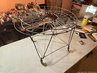 Full side view of the metal wire drying rack showing the spinning drying surface and wireframe stand with casters.
