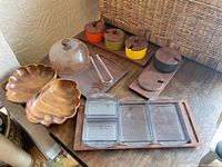 Full view of all tableware items on wooden surface, including wooden serving trays, glass dishes, spice jars, glass dome, and tongs.