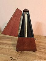 Front angled view of the vintage wooden metronome with the hinged door open showing the pendulum scale inside.