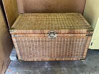 Front angle of the rectangular woven wicker chest showing the latch and corner protectors