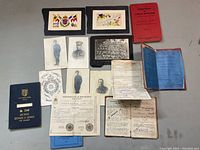 Overview of all items laid out: pay book, manuals, certificates, photos, postcards, diary pages