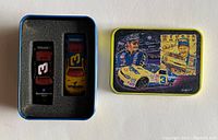 Two Dale Earnhardt NASCAR toy cars in foam insert inside tin box with blue interior