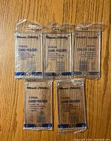 Photo showing five sealed Ultimate Collection sportscard screwdown holders arranged on a wooden surface.