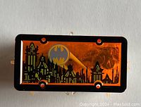 Decorative orange and black Batmobile license plate insert with Gotham City skyline and Batman logo.