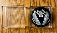 Top view of signed hockey puck inside display case showing Bobby Baun signature and inscriptions on Toronto Maple Leafs emblem.