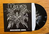 Front cover of the Misfits Descending Angel album with vinyl partially visible showing black and white splatter pattern.
