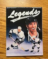 Front cover of Legends Sports Memorabilia magazine with Wayne Gretzky artwork showing three poses in white hockey gear, holding a hockey stick on a wooden surface.