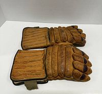 Top side view of the pair of brown leather 1940s hockey gloves showing padded finger sections and wrist protection flaps.