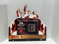 Front view of cardboard display with images of Olympic athletes, Canadian flags, Coca Cola branding, and 8 collectible coins embedded in a strip.