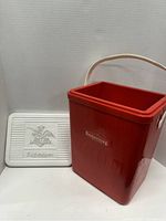 Open beer cooler showing red body and white lid embossed with Budweiser logo and eagle, visible wear and scuffs