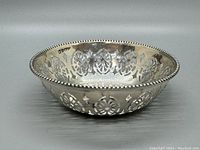Side angled view of the English sterling silver pin dish showing the pierced cutout floral pattern and beaded edge.