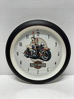 Front view of the Harley Davidson 2007 collector wall clock showing the motorcycle and female figure design on the clock face.