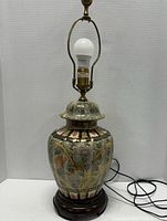 Full view of Japanese style pottery table lamp with light bulb, showing ceramic body and wooden base