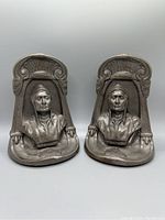 Front view of the pair of cast metal bookends depicting Native American busts with headdresses in detailed relief.