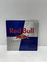 Front view of the Red Bull metal advertising sign with blue and silver quarters and red text logo