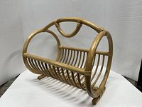Front angled view of Scandinavian rattan newspaper basket showing circular open sides and slatted base