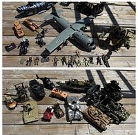 Top-down image showing full assortment of military toys with aircraft, helicopters, tanks, vehicles, and multiple small action figures lined up in front.