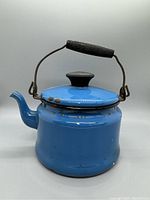 Front side view of the vintage blue enamel tea pot with black handle grip and knob lid.