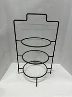 Full view of the black metal plate holder rack showing three round plate holders and handle design.