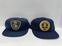 Pair of vintage OPP trucker baseball hats displayed side by side, showing front embroidered patches