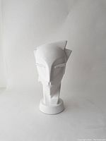 Front view of white ceramic Art Deco head sculpture with smooth surface and stylized angular facial features.