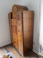 Closed front view of Art Deco wardrobe showing curved top and veneered finish