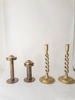 Photo of all four brass candlesticks showing two shorter straight-column sets and two taller twisted-column sets.