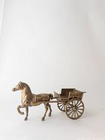 Side view of the brass horse attached to the buggy cart, showing details of horse and single cart with two wheels