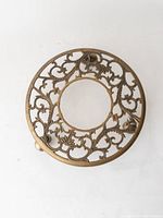 Top view showing the ornate circular brass plant stand with floral and leaf cutouts and a central opening for the plant pot.