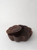 Top and side view of dark wood scalloped bowl with engraved floral lid partially covering the bowl.