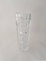 Front view of tall clear crystal vase with geometric cut patterns, showing its tapered shape and thick base.
