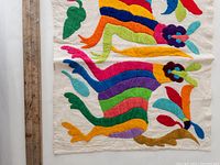 Close-up showing detail of the colorful embroidered animals and abstract embroidery on off-white fabric.