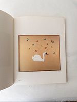 Open page of the art book showing a color artwork of a white swan on a tan background with abstract colorful shapes around it.