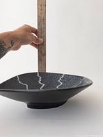 Side profile of the pottery dish showing depth and shape with a ruler for scale.