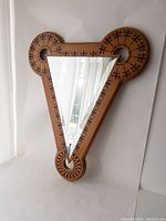 Full view of large triangular mirror with wood frame and circular geometric inlays.