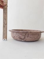 Side view of the pink marble bowl showing approximately 4 inch height with ruler for scale.