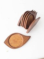 View of five wooden coasters with cork centers and wooden holder, coasters stacked in holder.