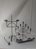 Image showing the two large black metal candleholders with multiple candle cups and central spike plus the candle snuffer.