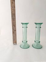 Two recycled glass candlesticks side by side with a ruler showing height approx 7 inches