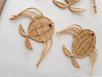 Front view of two wicker fish wall hangings lying flat on a light surface.