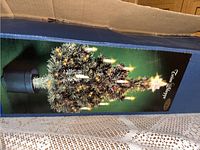 Photo of the 32 inch fibre optic tree in its original box, lit up with visual fibre optic lighting effects and star topper visible